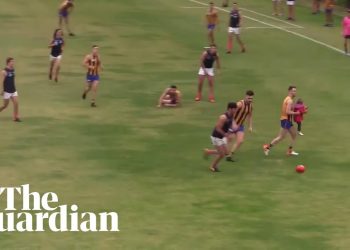 Toddler rescued by Aussie Rules player after running on to pitch during match