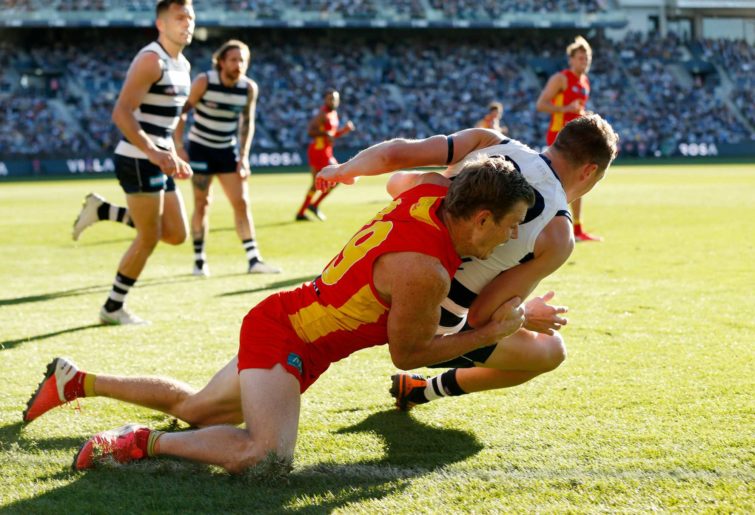Nick Holman of the Suns tackles Mitch Duncan 